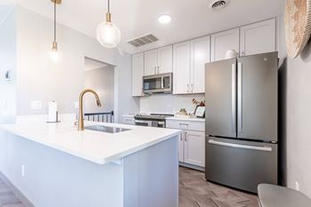 a white kitchen with stainless steel appliances and a white counter top